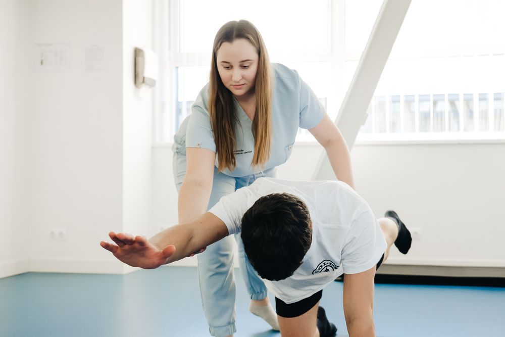Fisioterapeuta guiando un ejercicio de rehabilitación en una sala luminosa